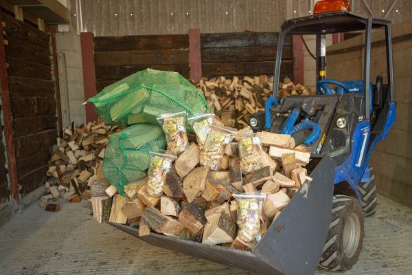 lots of logs in the bucket of a tractor